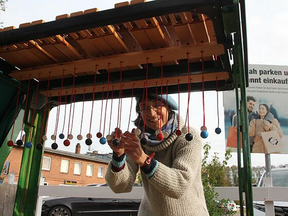 Die Straßenkünstlerin Monika Mayne  spielt auf einem selbstgebauten Ziehlophon. In der vergangenen Woche trat sie in der Bad Segeberger Fußgängerzone auf. Foto: ohe